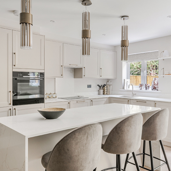 Photograph of kitchen at new house in Surrey The Waldrons. Three grey stools at kitchen island with light cabinets behind